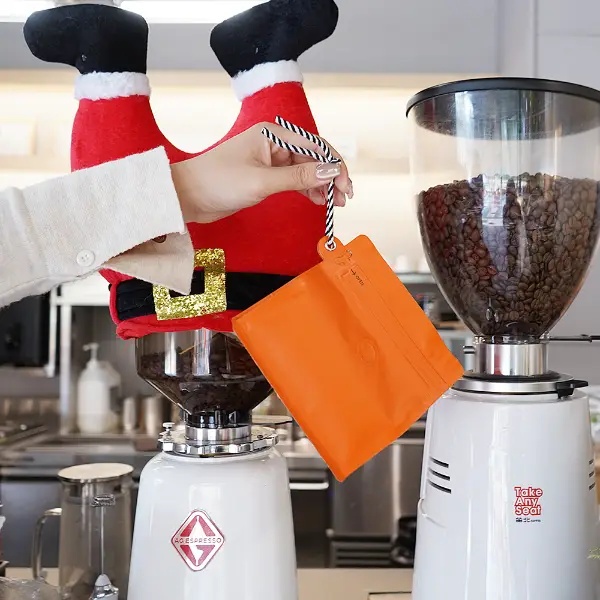 hand holding 150g stock coffee bags with lanyard in coffee shop